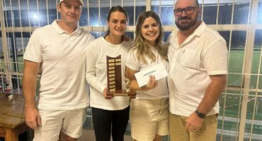 Group of four people celebrating tennis award indoors at Ridge Times.