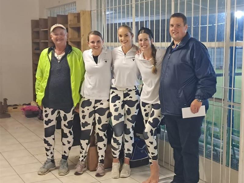 Young athletes in cow-print sportswear posing indoors with coach.