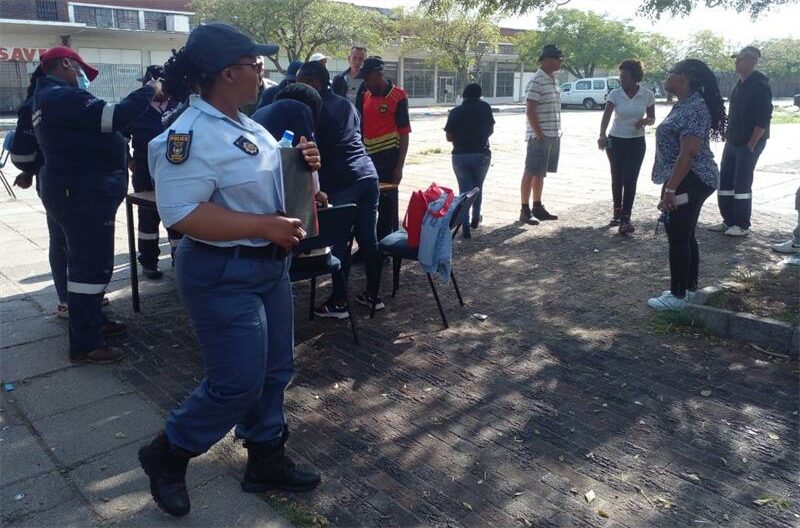 Police officer in uniform speaking to community members during a safety event.