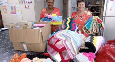 Handmade blankets and hats donated by volunteers for community support.
