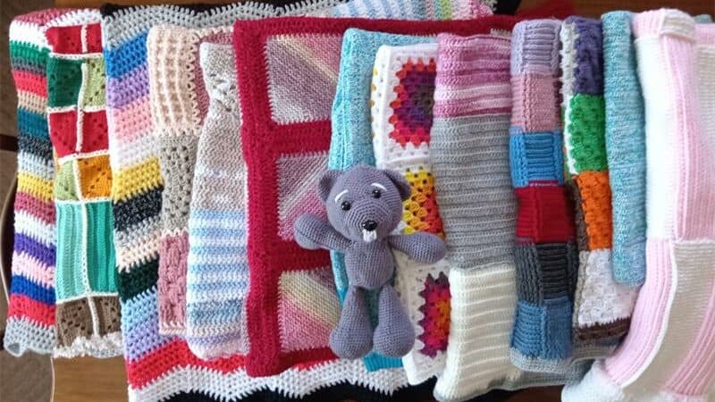 Brightly coloured handmade blankets with a grey teddy bear in the centre.