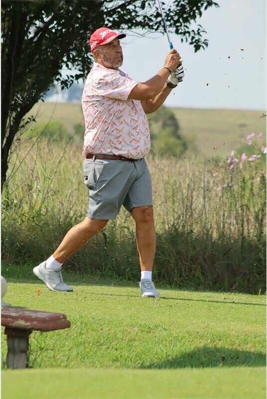 Golf player swinging club on course during daytime.