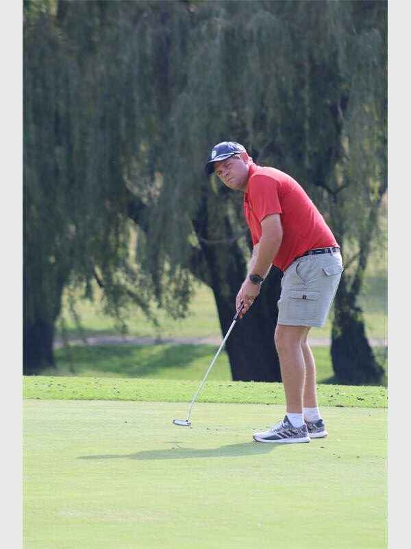 Golf player preparing to putt on the course with trees in the background.