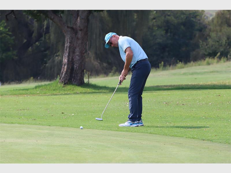Golf player lining up a putt on the lush green course.