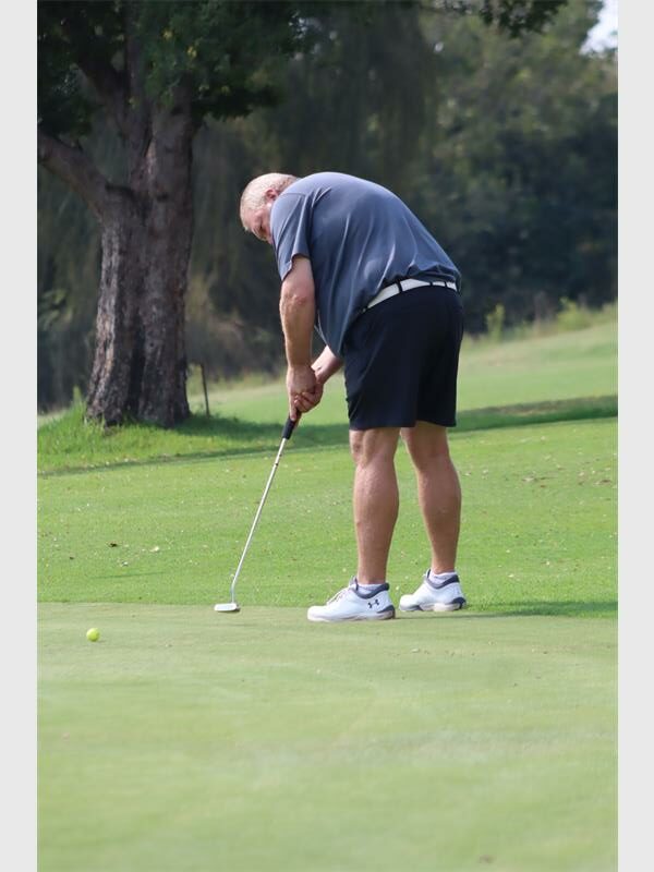 Senior man playing golf on the course, focusing on his shot.
