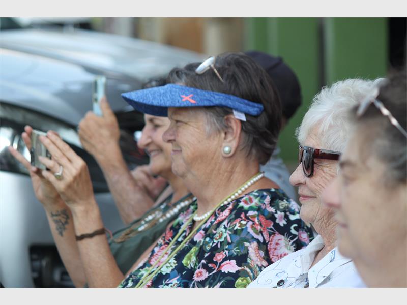 Elderly women smiling and taking photos at a community gathering or outdoor event.