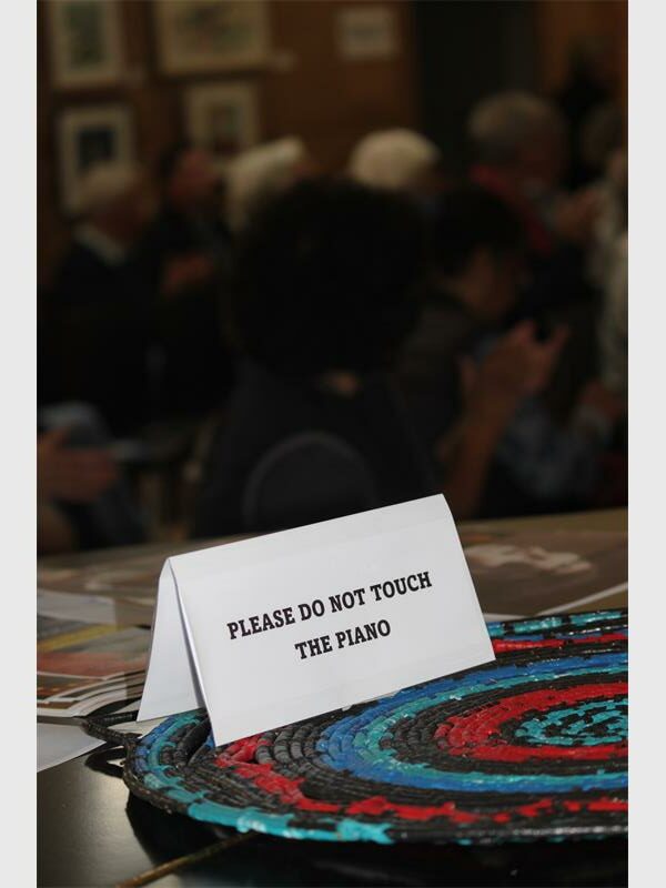 Warning sign on a table reading "Please do not touch the piano".
