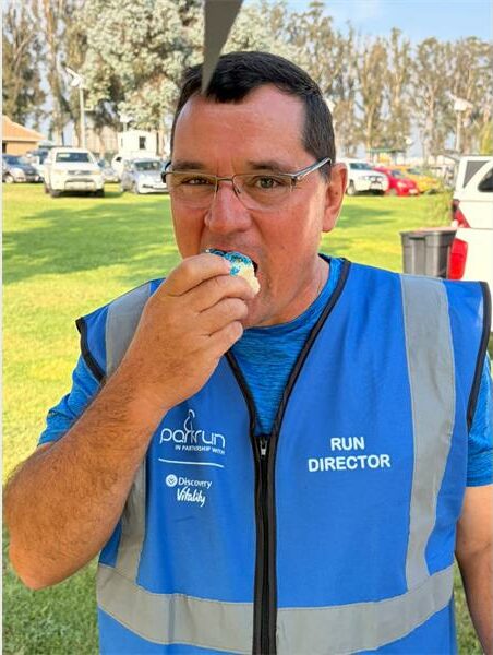 A man in a blue vest eats a piece of cake