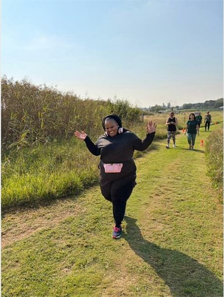 a woman in black runs in the park. She is holding up her hands