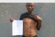 man with pulled up shirt points to scars on his stomach . he also has a paper in his hand
