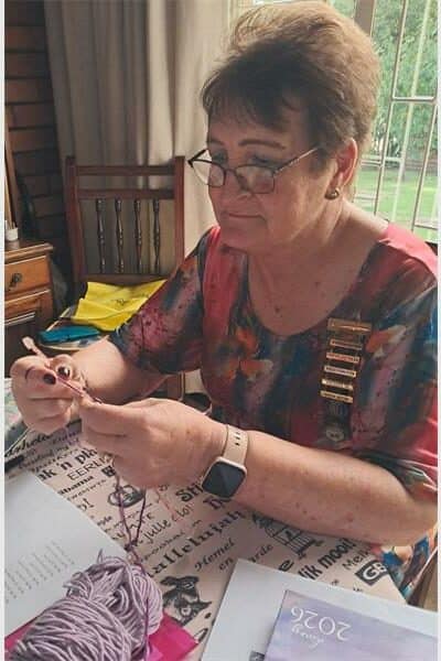 a woman with many badges on her chest is knitting something