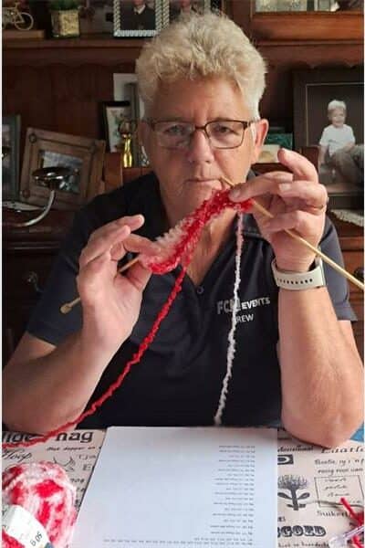 a woman with short grey hair is inspecting her knitting
