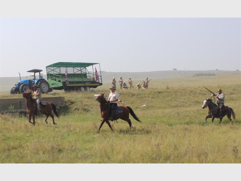 perde en ruiters in die veld met n trekker in die agtergrond