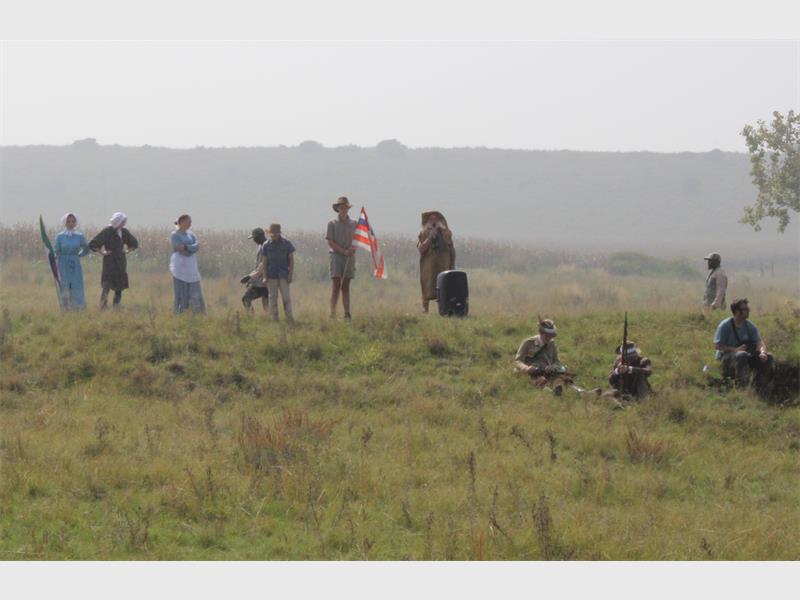 s 'n trekker en mense in die klere van Britse soldate in die veld