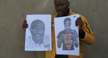 man holds up two pencil sketches