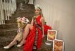 young model in a red dress wears a crown. A flower bouquet is in her hand.