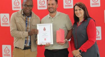 Three people with awards in front of a SANBS backdrop