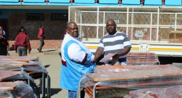 two men shake hands over school desks