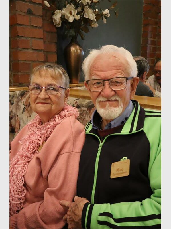 a woman in a pink jersey and a white headed man with a black and green jacket