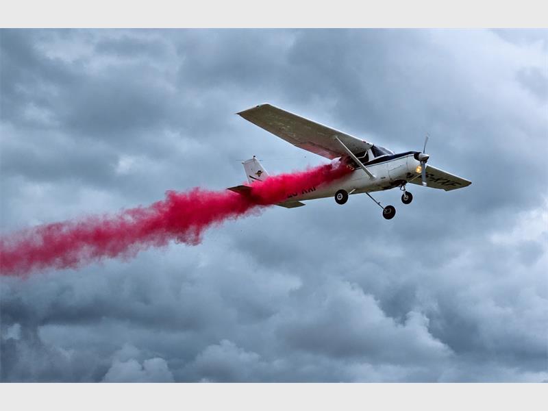 a light aircraft spraying a red trail