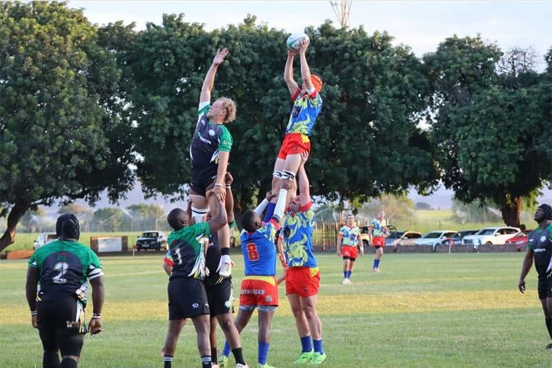 rugby teams jump for the ball in a line stand.