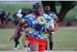 A rugby player with a scrum cap runs with the ball