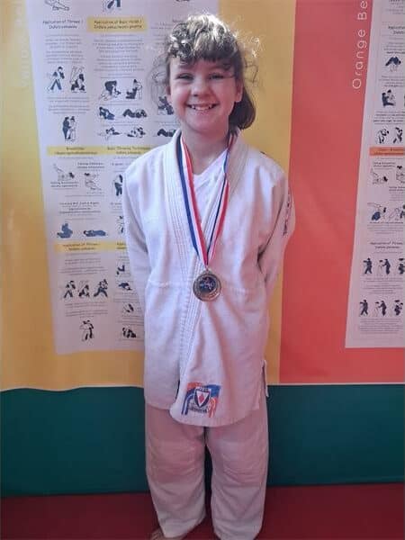 a girl in judo clothes with a medal around her neck