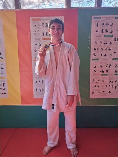 a boy in judo clothes with a medal around his neck