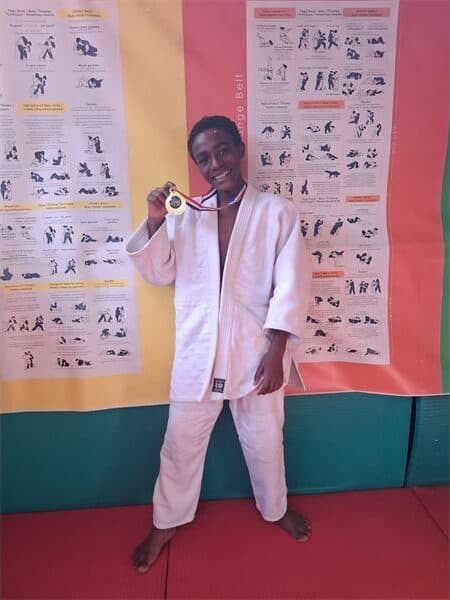 a boy in judo clothes with a medal around his neck