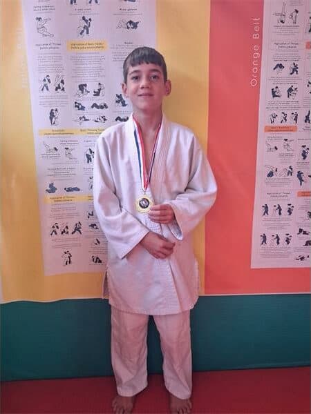 a boy in judo clothes with a medal around his neck