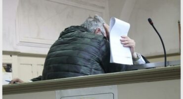 a man in the court dock covers his face