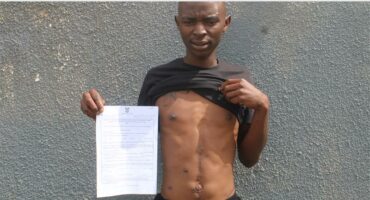 man with a paper and bullet wounds in his stomach