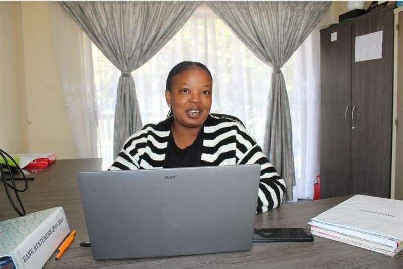a woman sitting at a desk behind her laptop