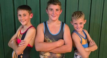 three boys in wrestling outfits