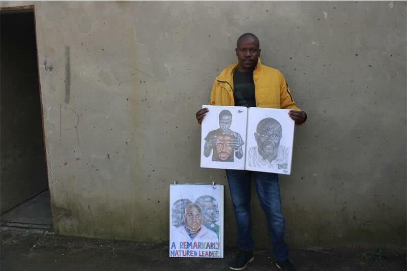 man holds up two pencil sketches