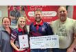 two women and two men with a certificate and a large cheque