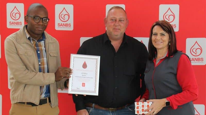Three people with awards in front of a SANBS backdrop