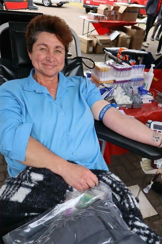 a woman in a blue blouse donates blood