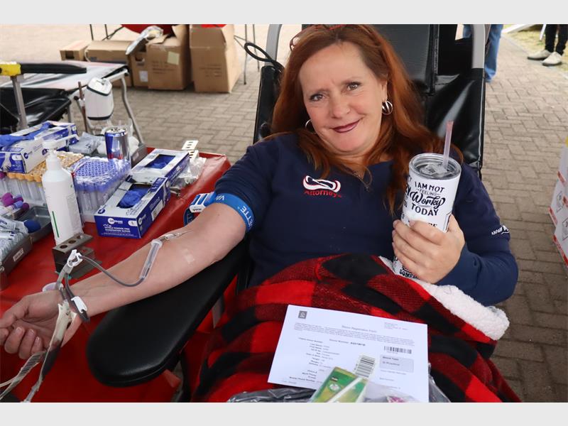 woman holds a cup in her hand while she donates blood