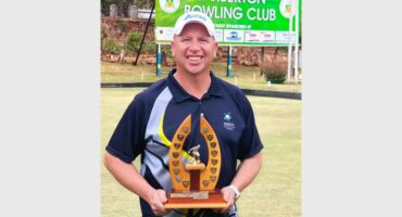 man in blue sports wear holds up a trophy