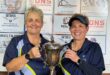 Two women hold up a trophy