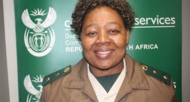 woman in correctional services uniform standing in front of a green backdrop