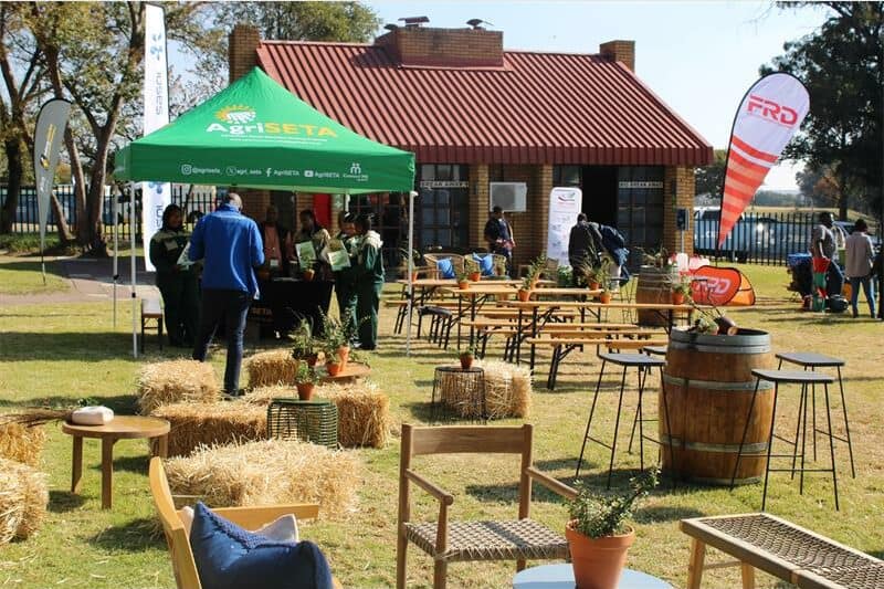 an open area with bales of hay, a wooden barrel and tents