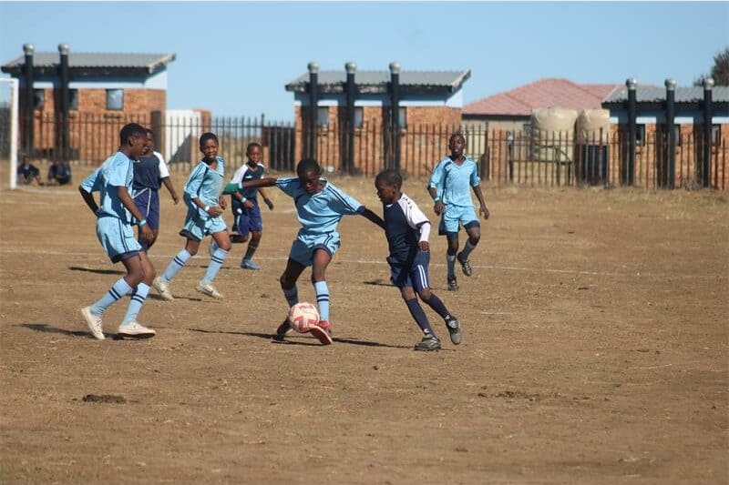 two teams of young soccer players compete for the ball.