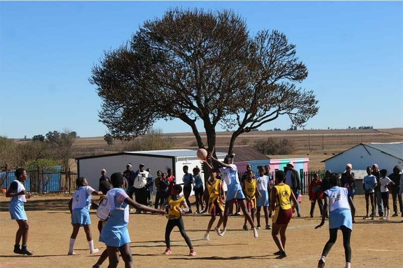 two teams of young netball players compete for the ball.