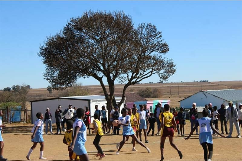 two teams of young netball players compete for the ball.