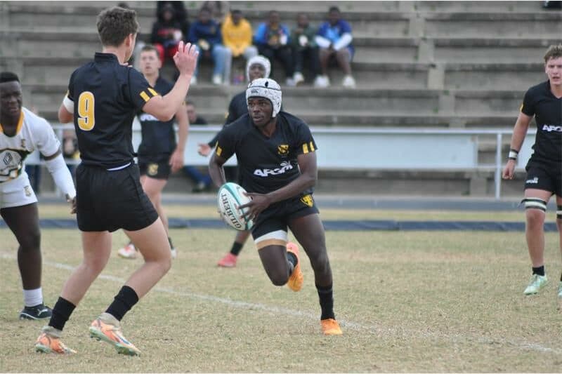 a boy in black and white rugby jersey runs at full speed