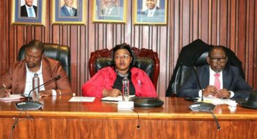 Two men and a woman sitting at the council mayoral bench