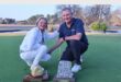 two people with trophies on a golfing greens