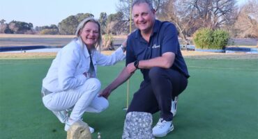 two people with trophies on a golfing greens